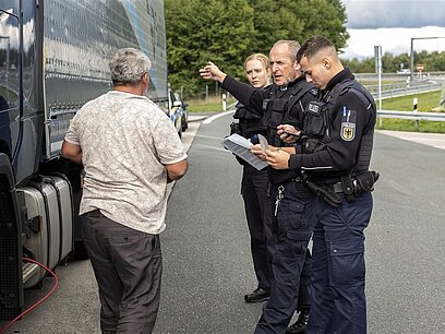 Zwei Polizisten befragen einen Lkw-Fahrer.