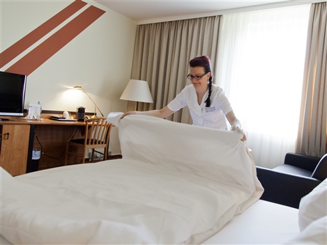 Eine Hotelfachfrau macht ein Bett.