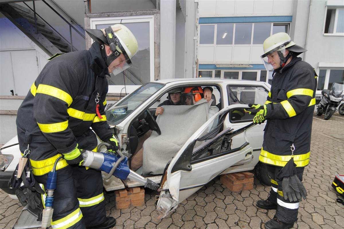 Zwei Feuerwehrleute öffnen die Tür eines Unfallwagens.