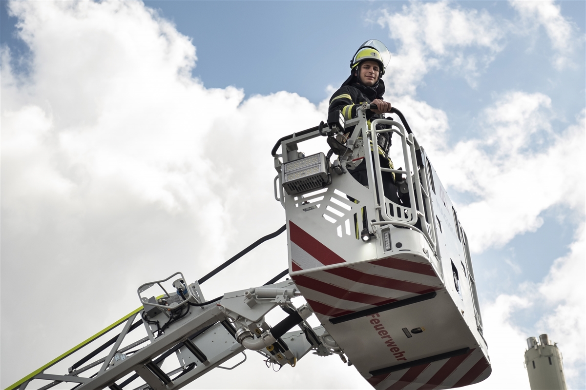 Ein Feuerwehrmann steht in einem Rettungskorb, der nach oben gefahren wird.