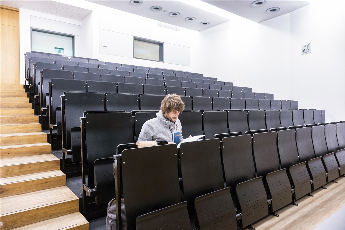 Ein Student sitzt in einem leeren Hörsaal.