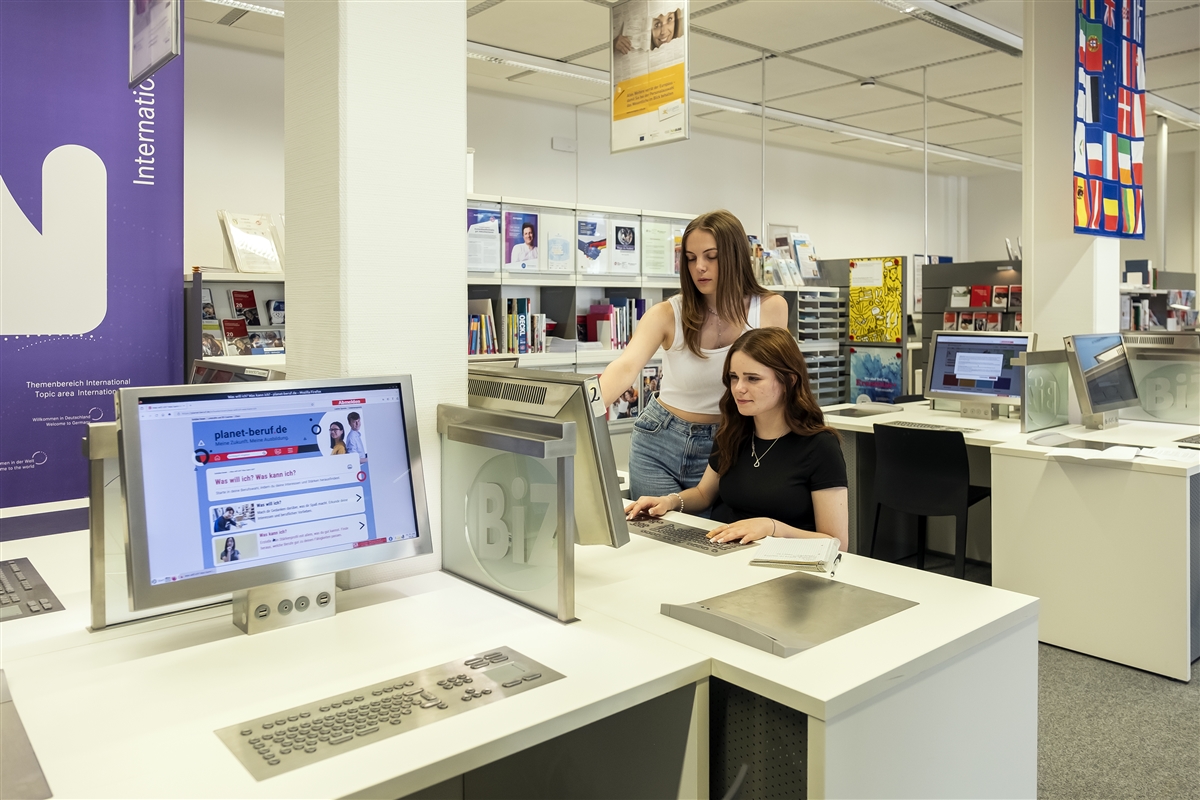 Zwei junge Frauen informieren sich an einem Computer im Berufsinformationszentrum zur Berufswahl.