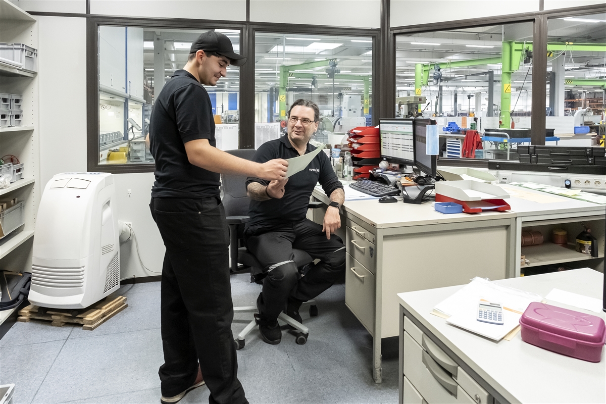 Batuhan und sein Ausbilder sprechen im Büro über die Unterlagen zum heutigen Auftrag.