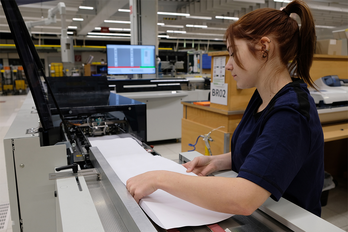 Alyssa legt die Dokumente in die Kuvertiermaschine.