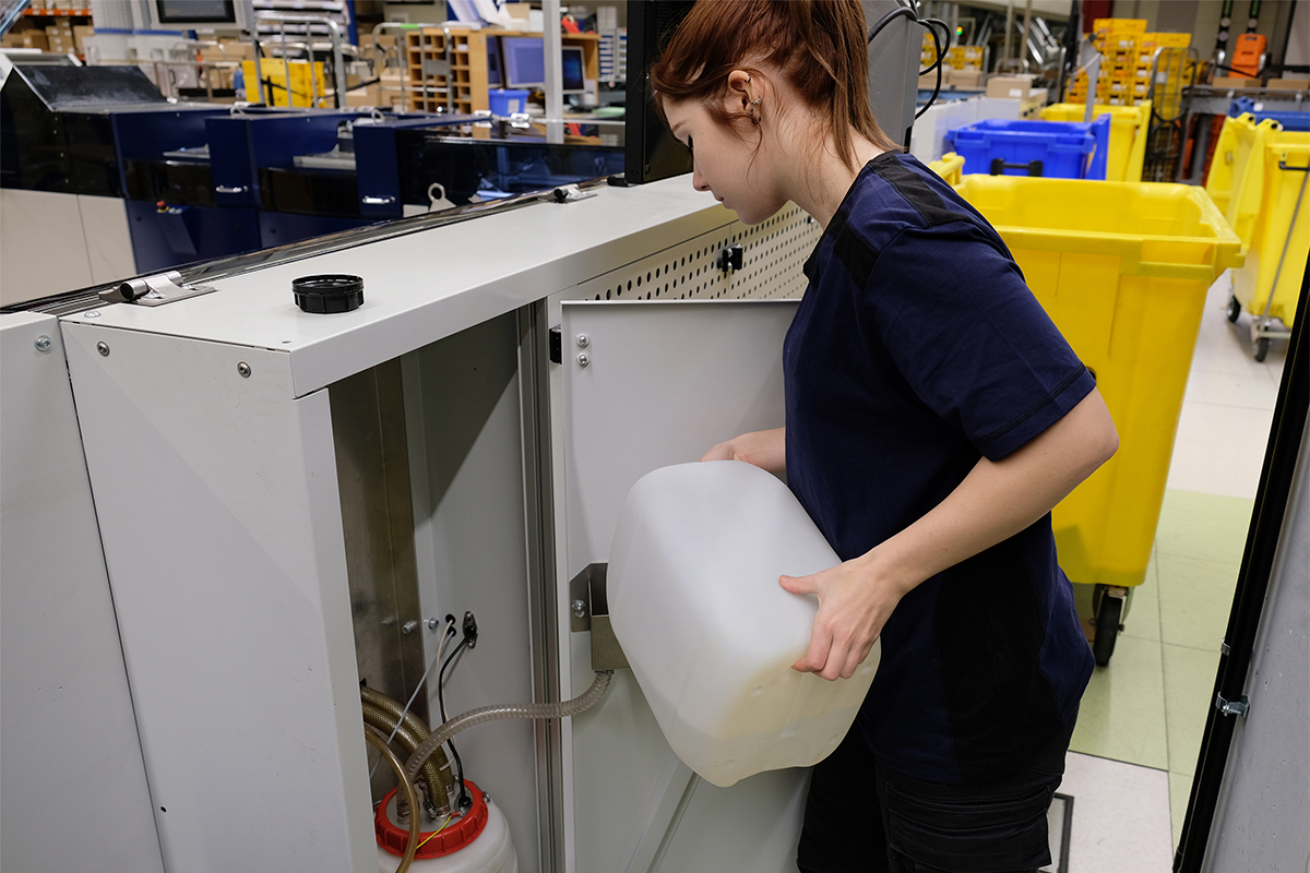 Alyssa füllt den Wassertank der Kuvertiermarschine auf.