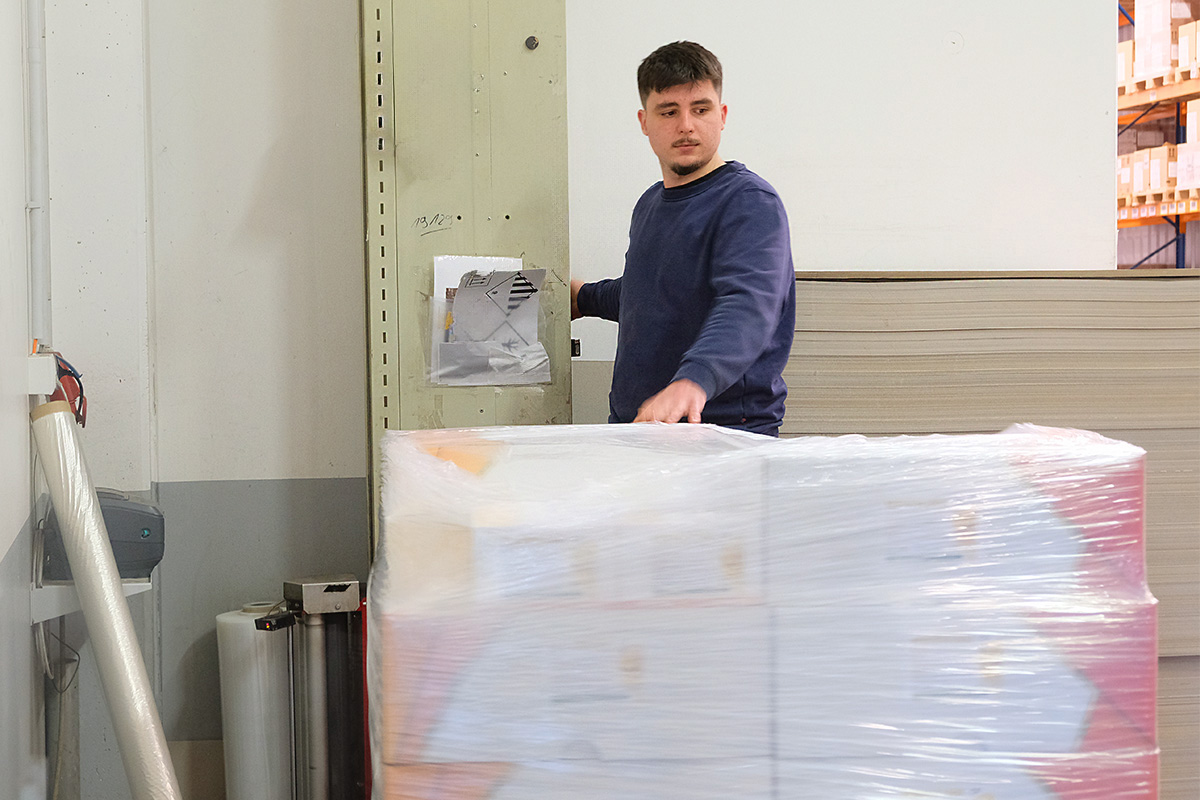 Maciej verpackt eine fertig beladene Palette mit Folie.
