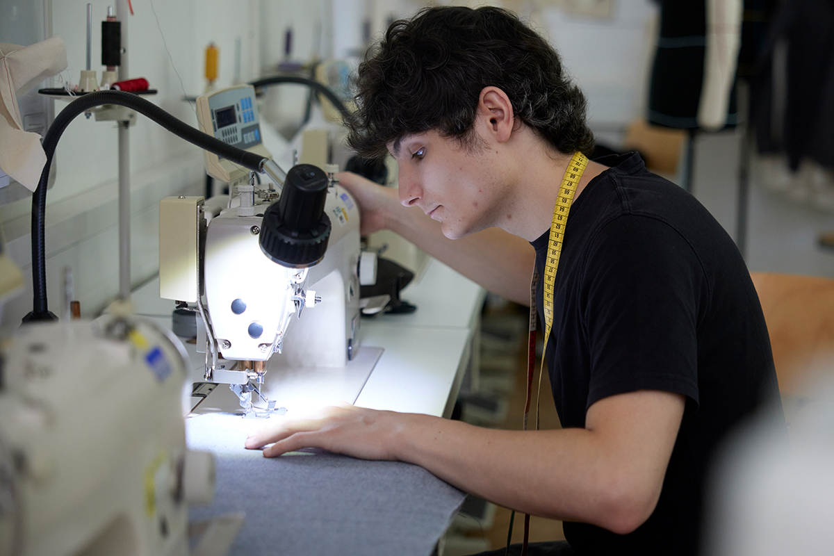 In der Werkstatt näht Paul Stoffteile mit einer Nähmaschine zusammen.