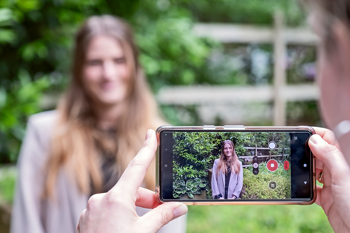 Eine Person filmt eine andere Person mit einem Smartphone.